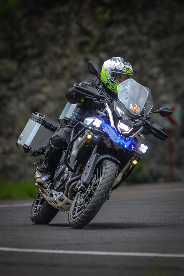 Biker navigating a sharp curve on a motorcycle with adventure gear, emphasizing safety and thrill.